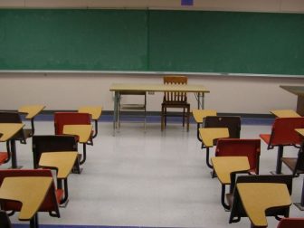Chalkboard and desks are seen in an empty classroom.