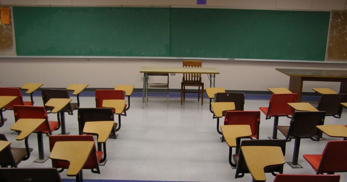 Chalkboard and desks are seen in an empty classroom.