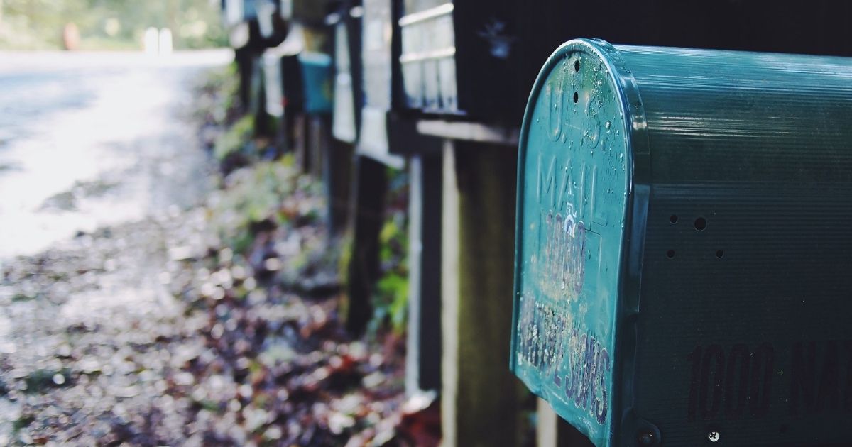 Line of mailboxes to the side of a road.