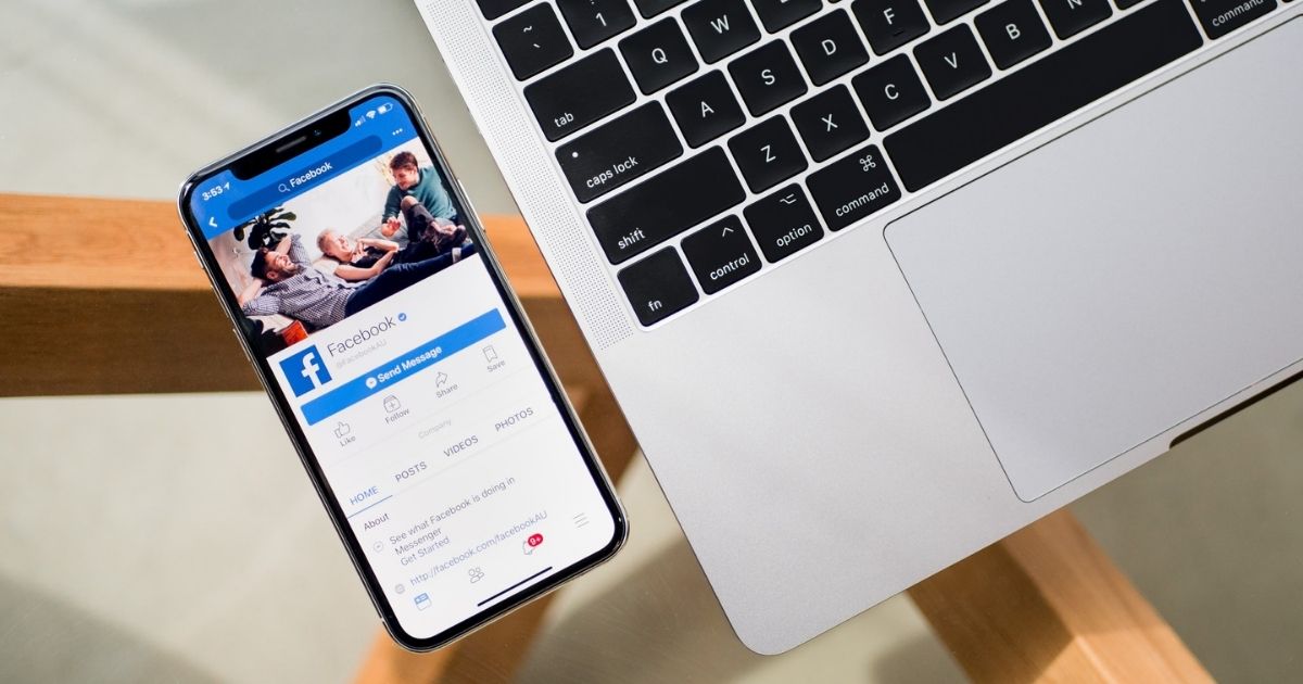 Mobile Facebook app on an iPhone next to a MacBook on a table