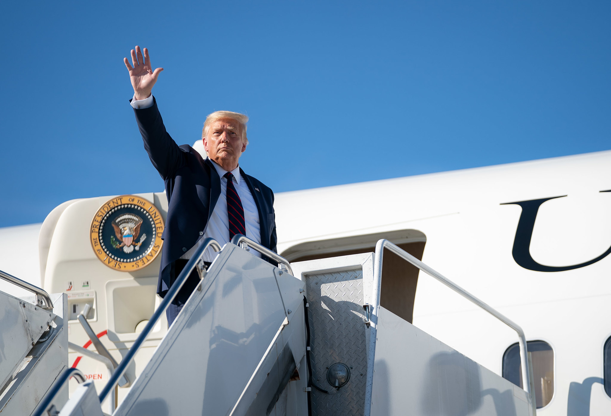 President Trump waves as he debarks Air Force One