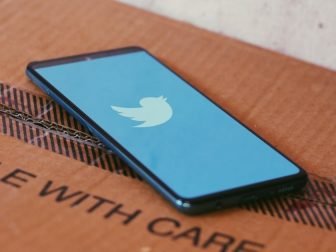 Twitter loading screen on a smartphone sitting on a cardboard box.