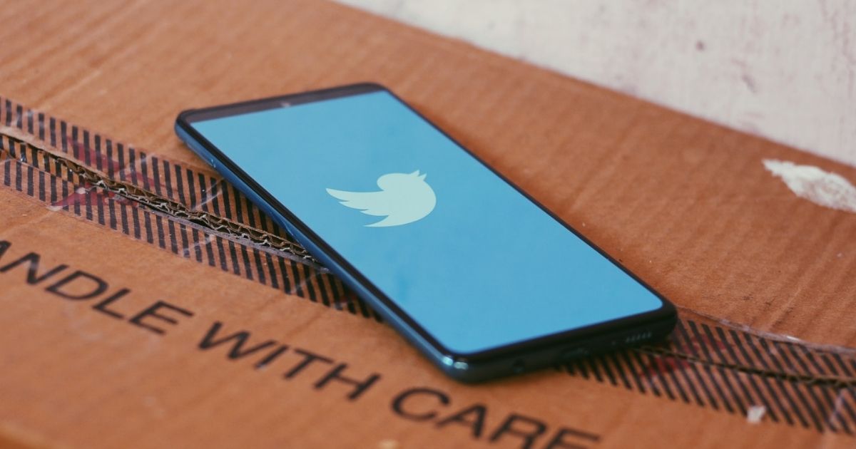 Twitter loading screen on a smartphone sitting on a cardboard box.