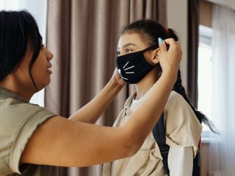 Mother putting face mask on her daughter