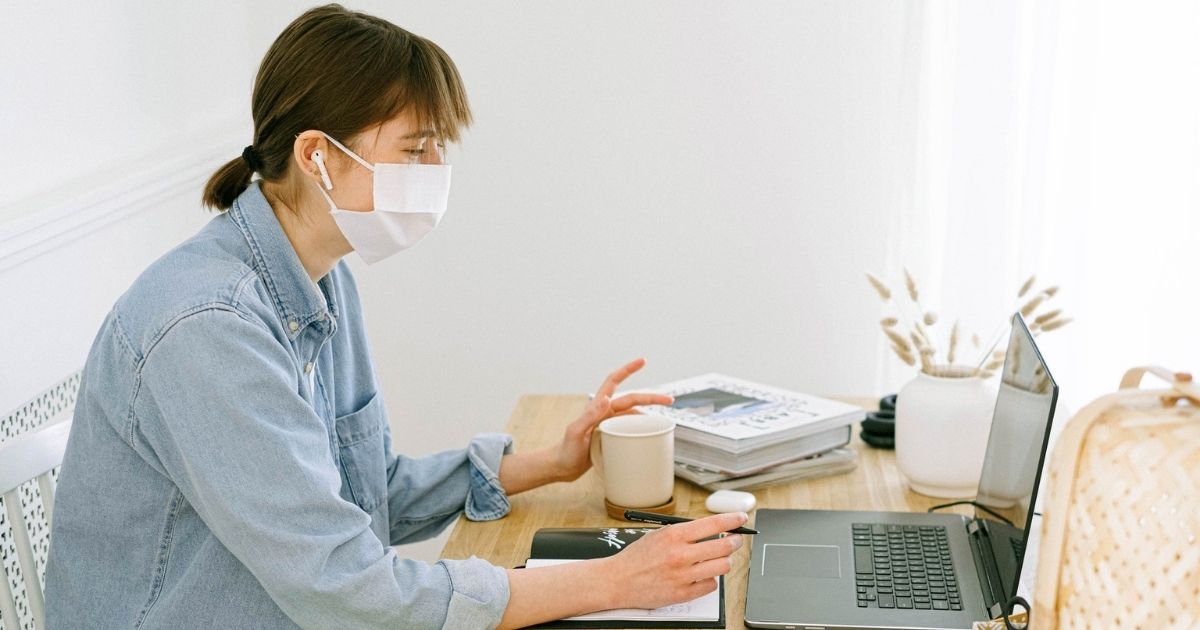 Woman wearing face mask while working from home