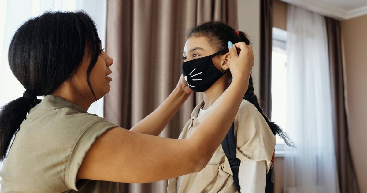 Mother putting face mask on her daughter