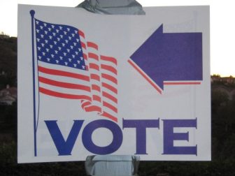 The above stock image shows a sign pointing to where people can go vote.