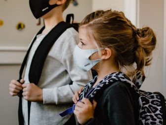 Two kids standing side by side wearing masks