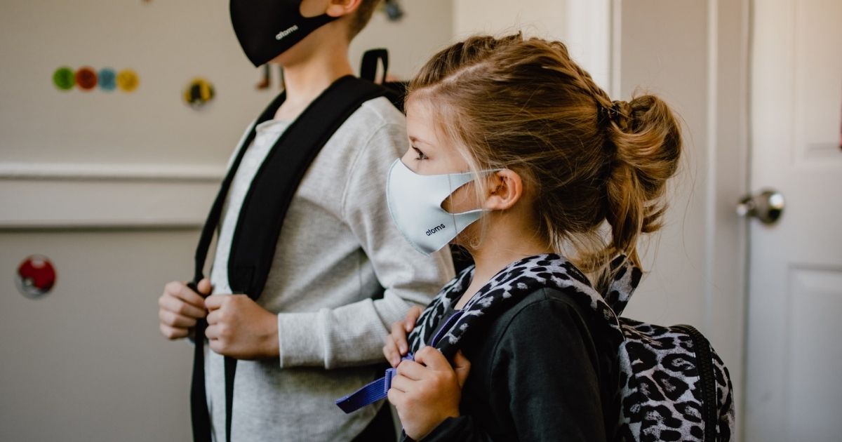 Two kids standing side by side wearing masks