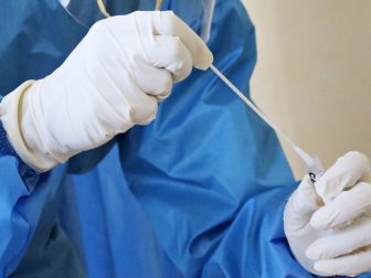 A laboratory worker takes a swab test