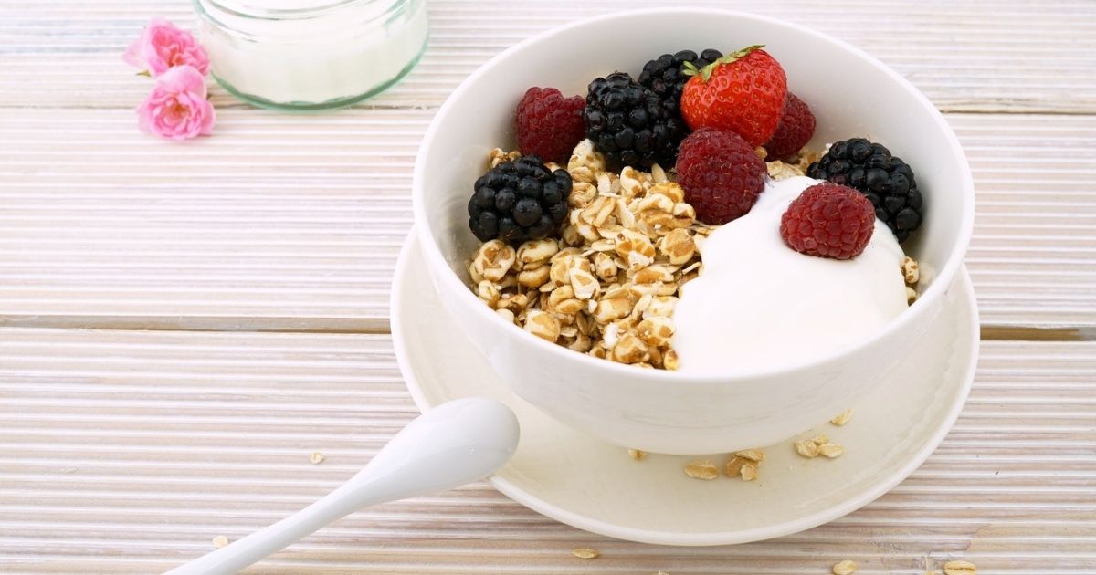 A bowl of yogurt with granola and fresh berries