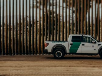 The border wall and a border patrol truck are seen in this photo.