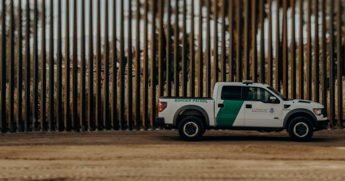 The border wall and a border patrol truck are seen in this photo.
