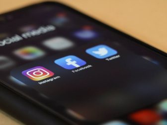 Black iPhone displaying Instagram, Facebook and Twitter apps
