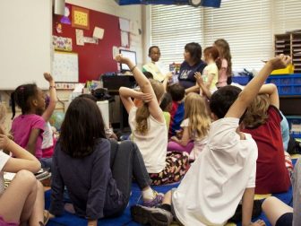 Captured in a metropolitan Atlanta, Georgia primary school, this photograph depicts a typical classroom scene, where an audience of school children were seated on the floor before a teacher at the front of the room, who was reading an illustrated storybook, during one of the scheduled classroom sessions.