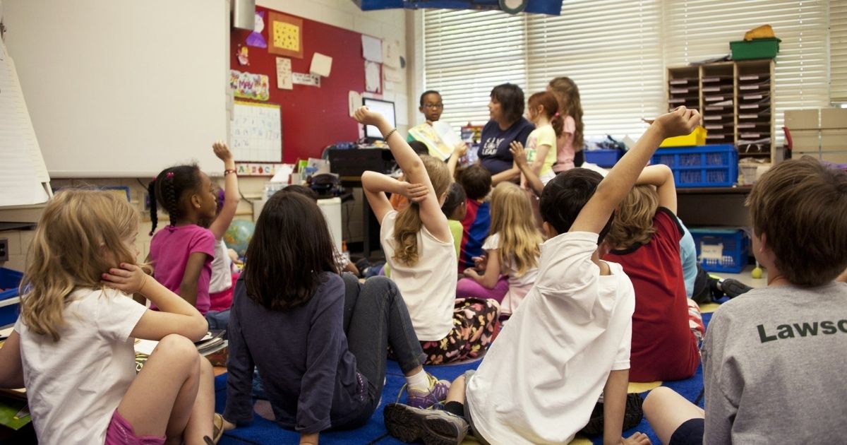 Captured in a metropolitan Atlanta, Georgia primary school, this photograph depicts a typical classroom scene, where an audience of school children were seated on the floor before a teacher at the front of the room, who was reading an illustrated storybook, during one of the scheduled classroom sessions.