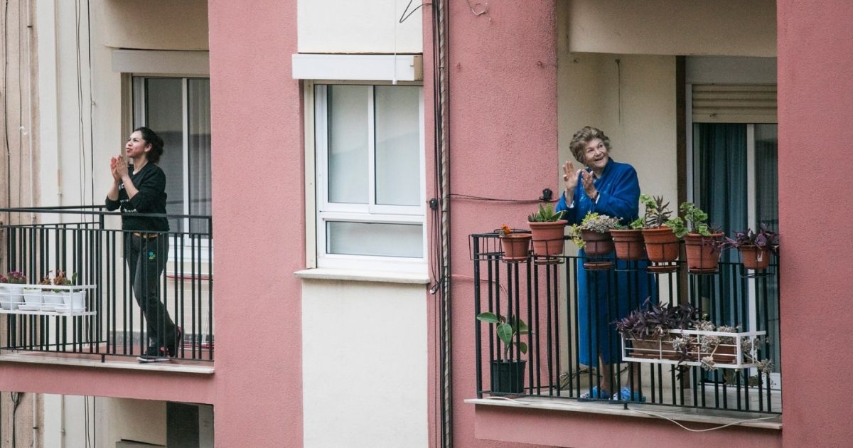 People standing on apartment balconies in lockdown.