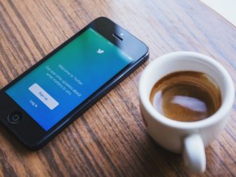 Phone on a table with the Twitter login screen next to a cup of coffee