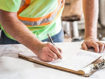 Construction worker writing on a clipboard