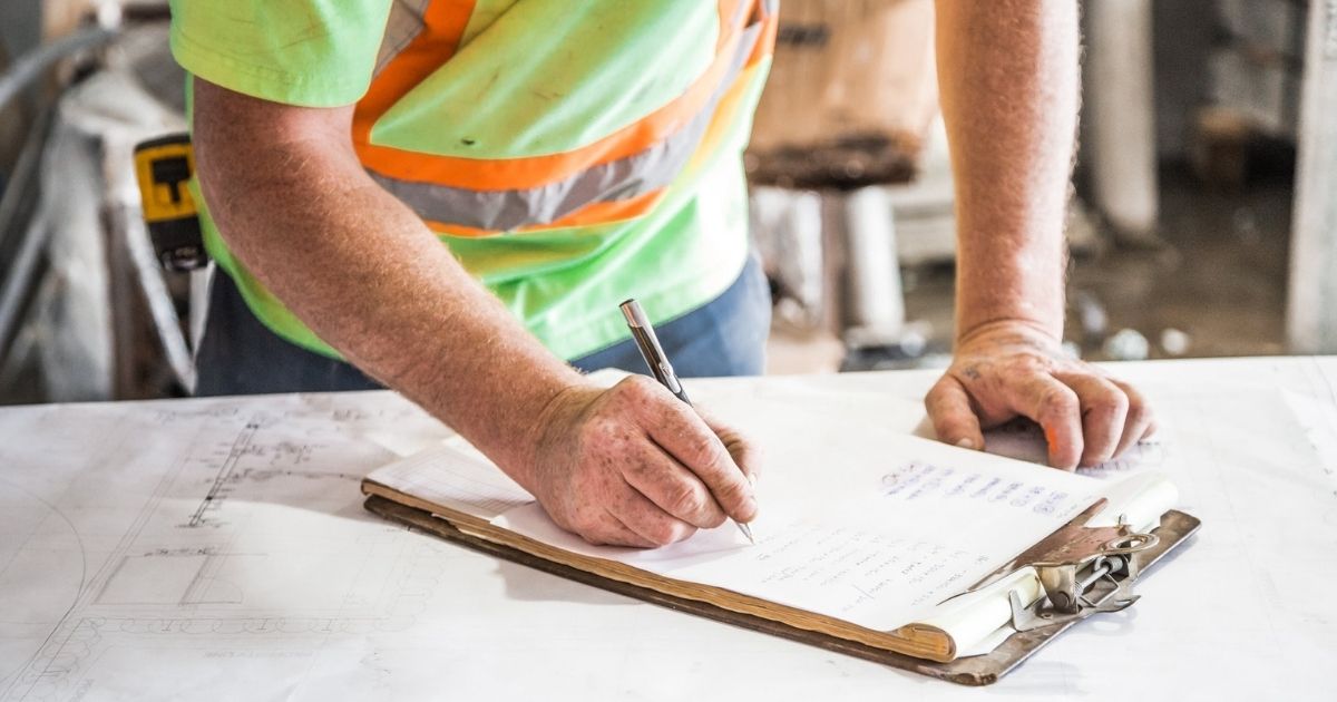 Construction worker writing on a clipboard