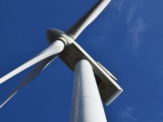 Looking up at a wind turbine against a blue sky