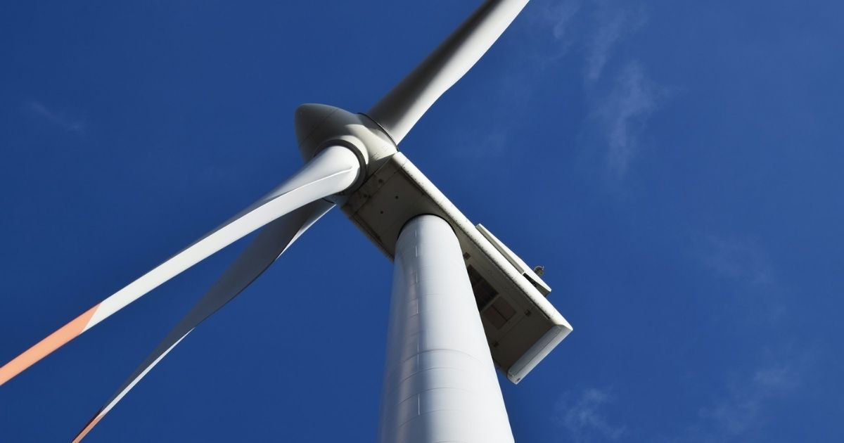 Looking up at a wind turbine against a blue sky