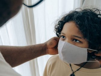 Man helping a child put a mask on