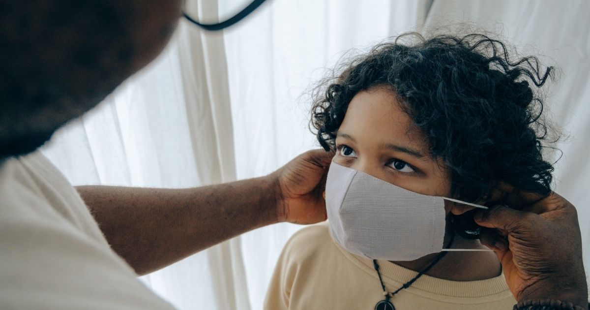 Man helping a child put a mask on