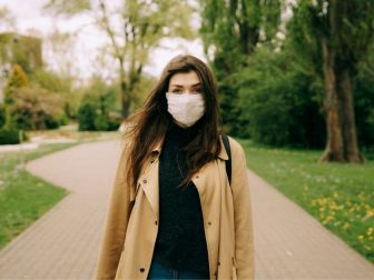 Girl walking through park in a mask