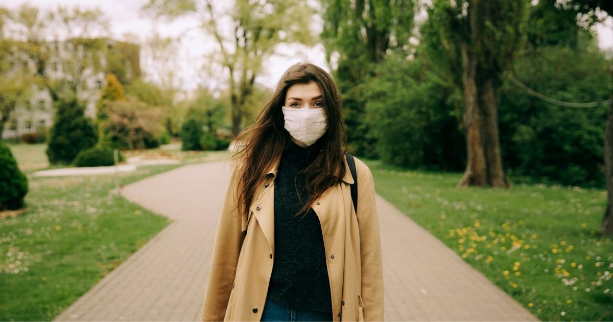 Girl walking through park in a mask