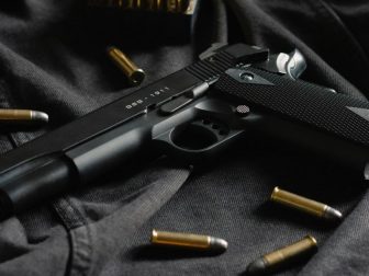 A black handgun on black cloth, with ammunition