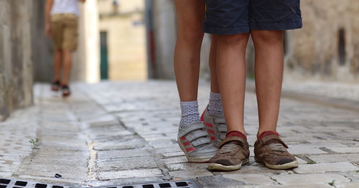 Shoes of a young boy and girl on a road.