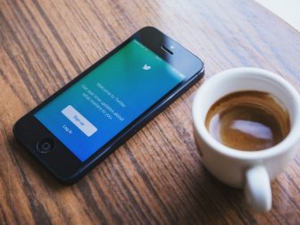 Twitter login screen on a phone sitting next to a cup of espresso