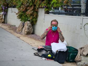 A homeless man puts on his face mask during the COIVD outbreak.