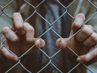 Hands clinging to a fence