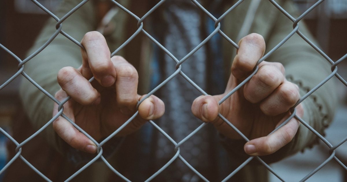 Hands clinging to a fence