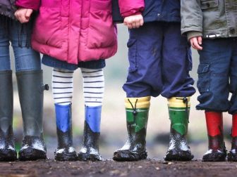 Four kids wearing muddy rain boots