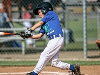 Little League baseball player connects with a pitch