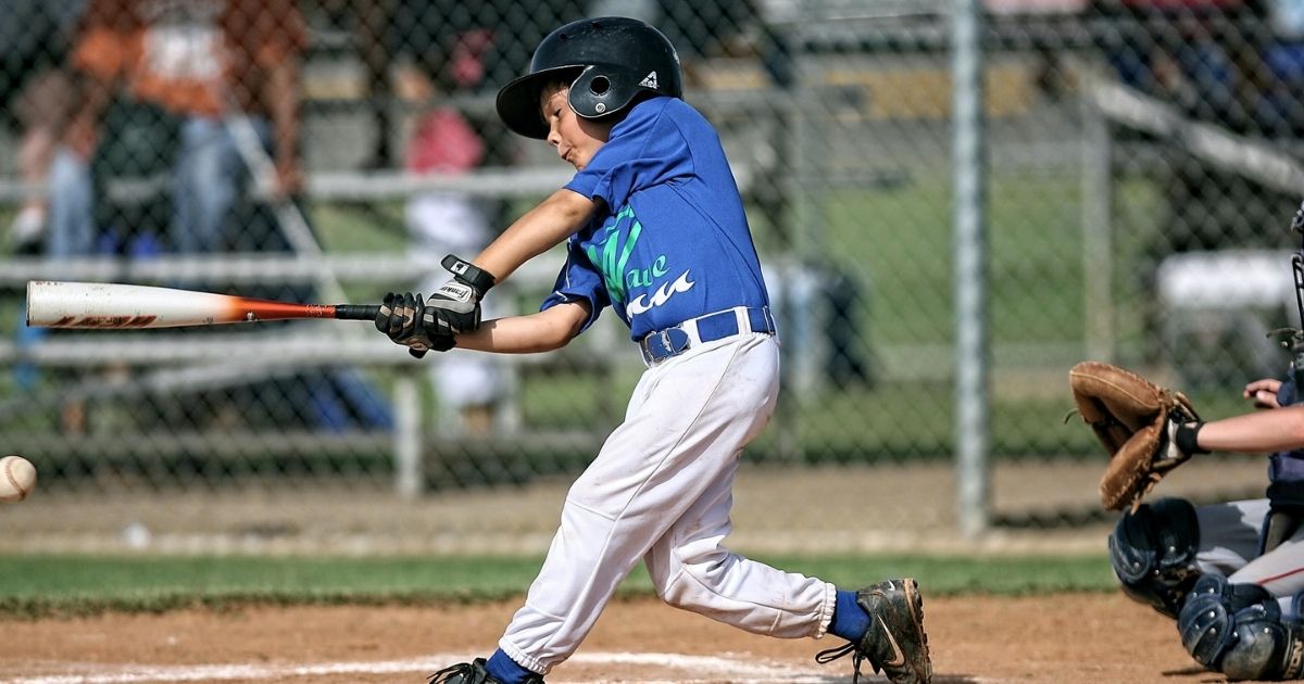 Little League baseball player connects with a pitch