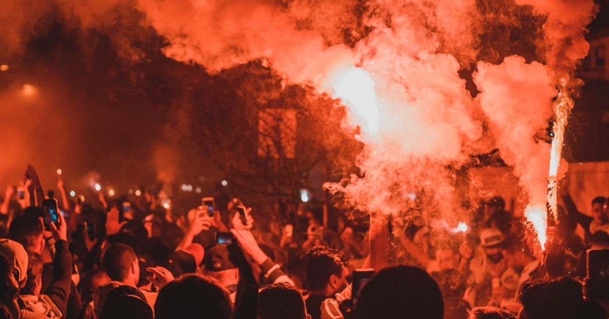 People on the street during a riot with smoke and fire.