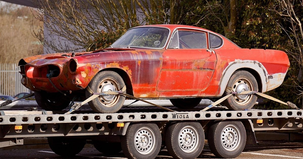 Old red car being towed
