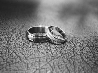 Silver wedding bands on a black surface