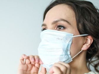Woman putting on a disposable facemask