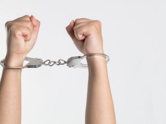Person holding up hands in hand cuffs