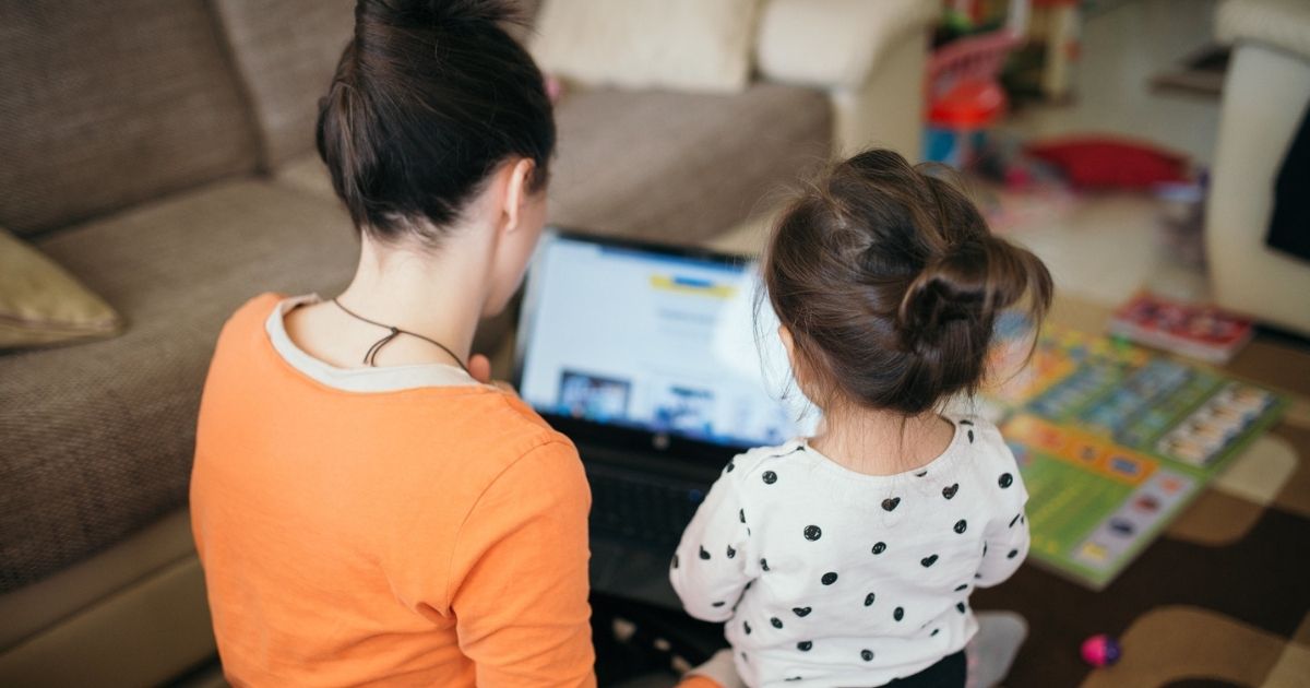 Mom teaches daughter for work on laptop.