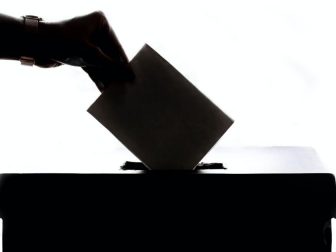 Hand putting ballot into a box