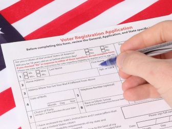Man filling out Voter Registration Application with USA flag in background