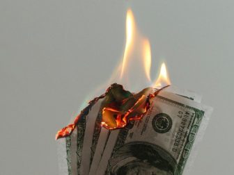 Hand holding dollar bills on fire
