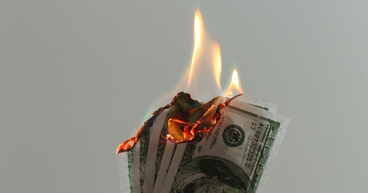 Hand holding dollar bills on fire