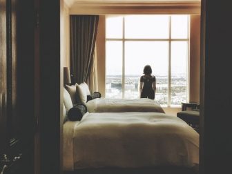 Dark hotel room with a woman standing in the window